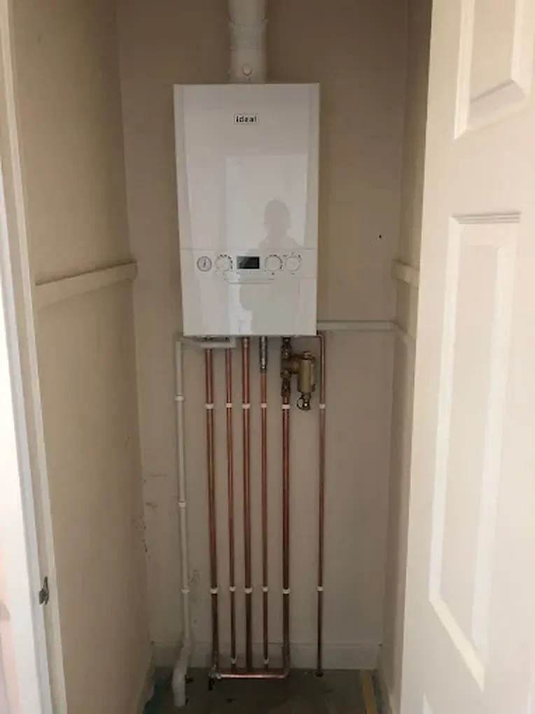 Ideal boiler fitted in a hall cupboard with copper pipework